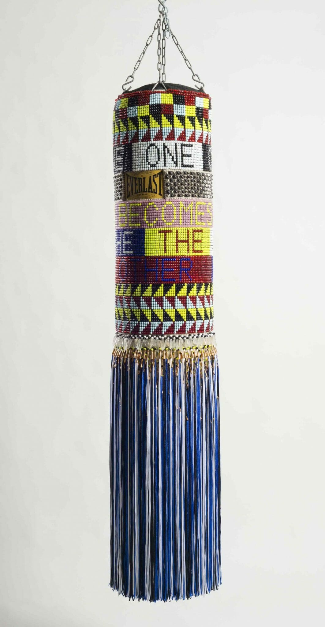 Jeffrey Gibson (Mississippi Band Choctaw/ Cherokee), ONE BECOMES THE OTHER, 2015. Repurposed wool army blanket, repurposed punching bag, glass beads, plastic beads, steel studs, artificial sinew, quartz crystals, copper cones, nylon fringe, steel, and acrylic paint; 73 × 16½ × 16½ in. Private collection, courtesy of Marc Straus Gallery, New York. Image courtesy of Jeffrey Gibson Studio and Roberts Projects, Los Angeles, California. Photograph by Peter Mauney.