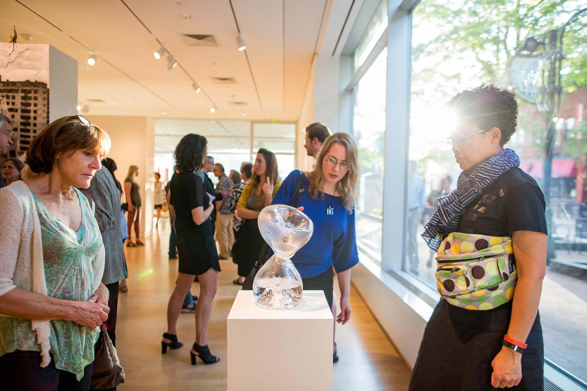 Visitors enjoying an MMoCA Opening, looking at a work shaped like an hour glass. Photo by Sharon Vanorny.