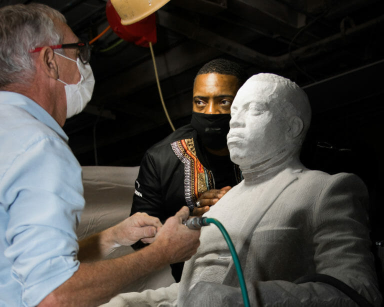 Sculptor works on a sculpture while the model Faisal Abdu'Allah is standing next to it