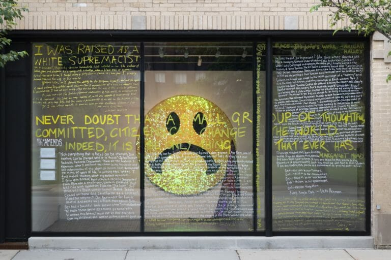 the windows with writing on the front of the Madison Museum of Contemporary Art, showing part of the AMENDs exhibition inside the building