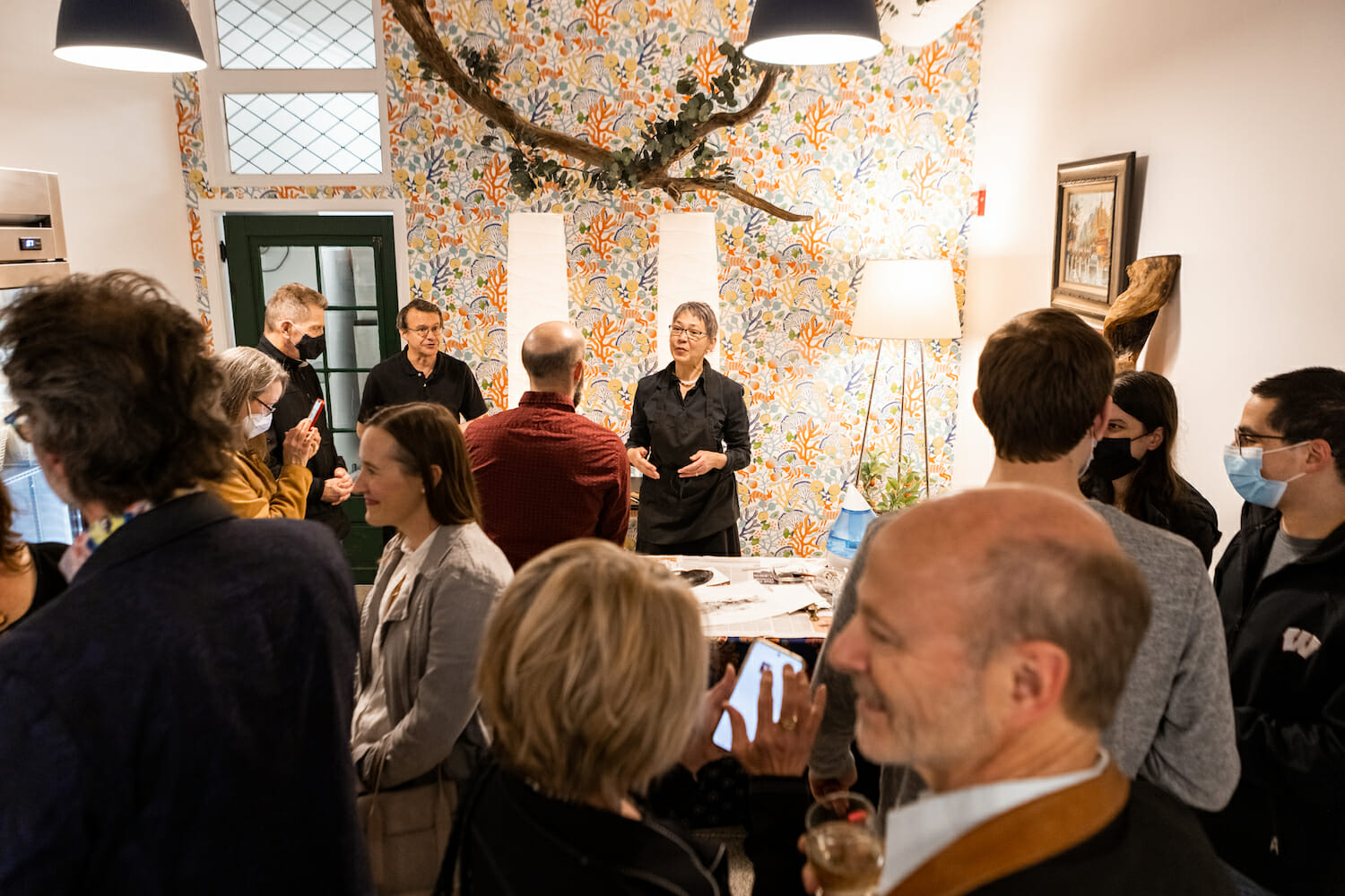 people gathered in the back of the store, either chatting with others or watching an artist print demonstration with fish