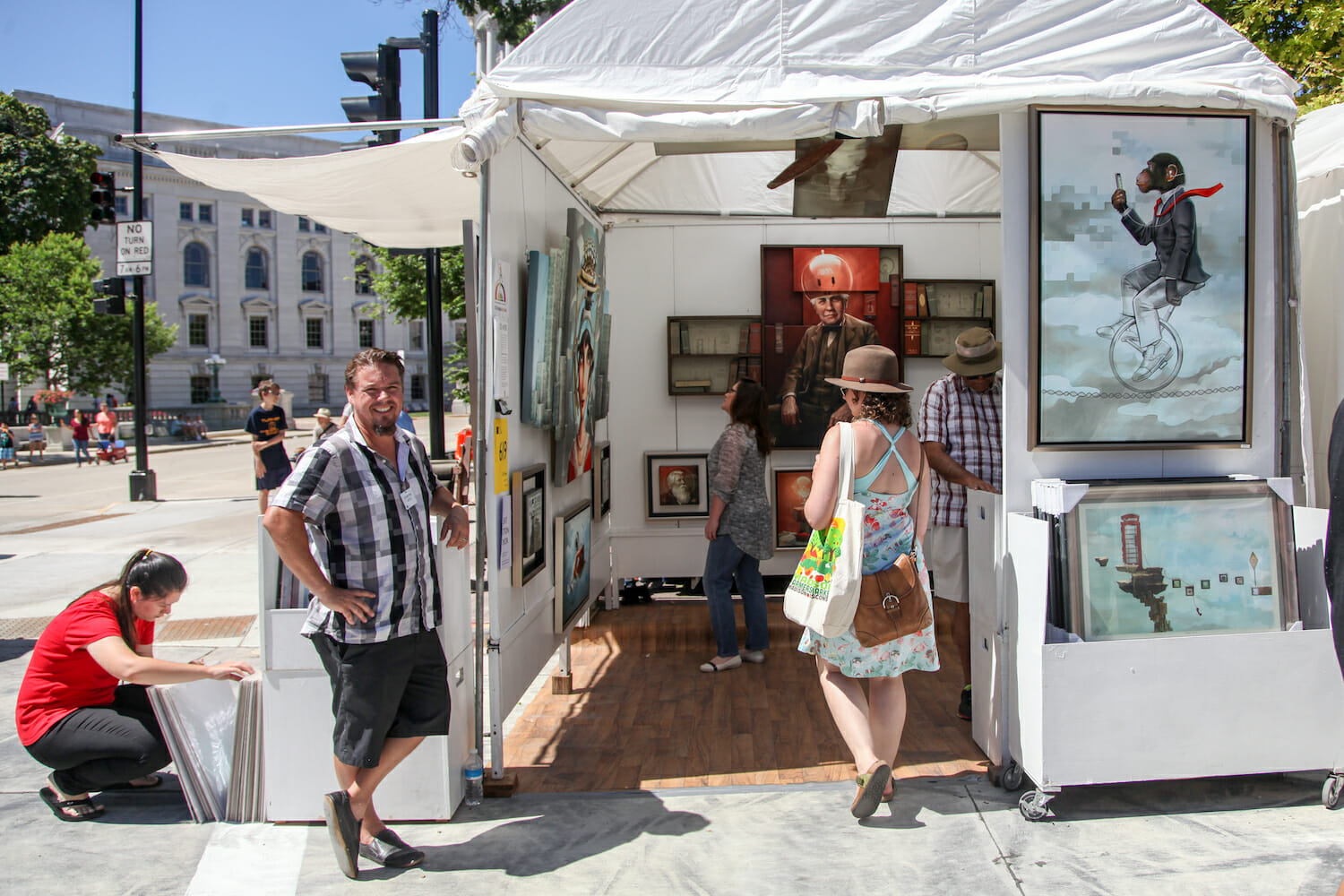 artist standing outside of their booth while Art Fair visitors browse the paintings