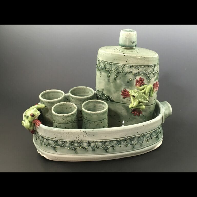 ceramic set with four smaller cups, a larger container, and a tray. Small frog figurines attached to the tray and large container.