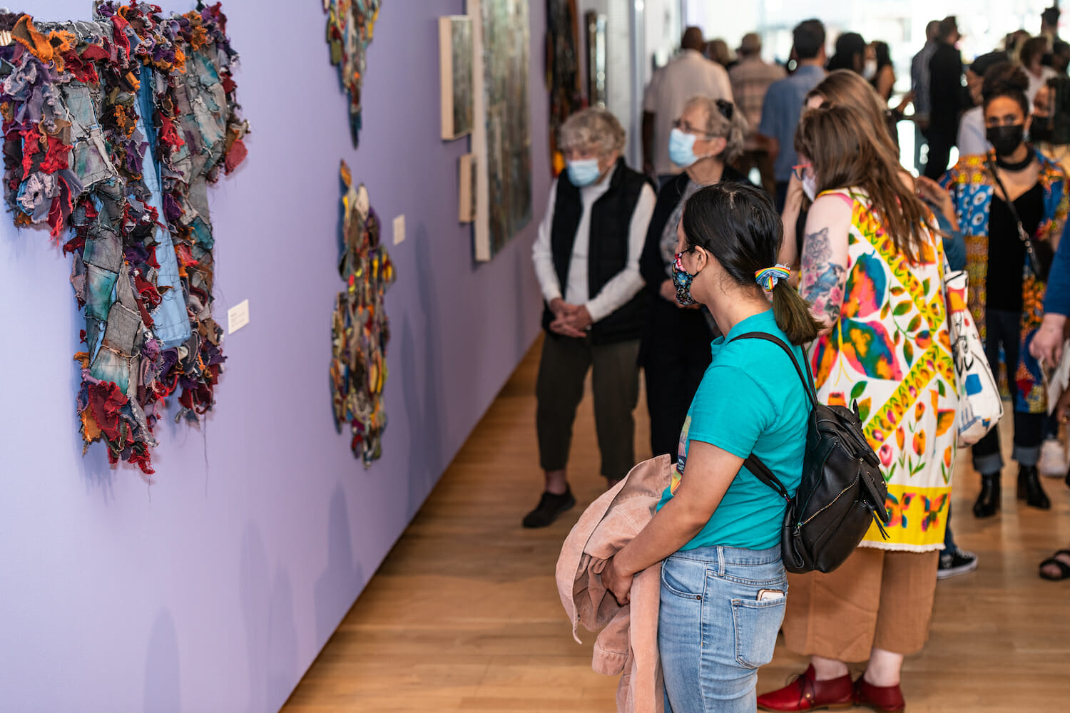 people looking at textile artwork on the wall