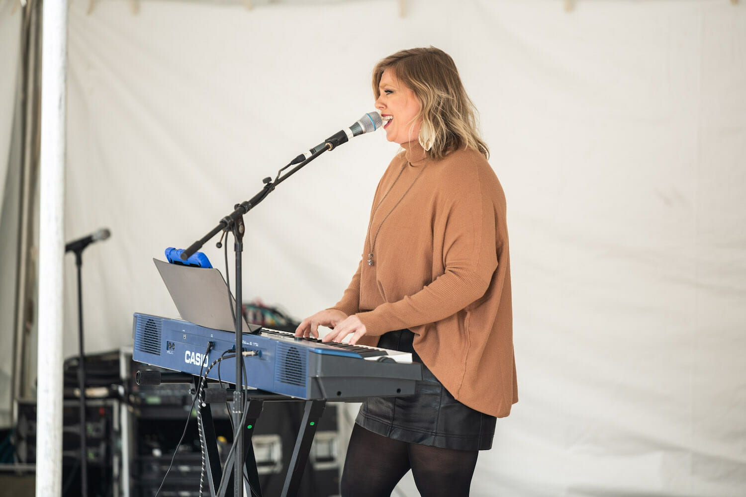 performer singing into a microphone while playing piano