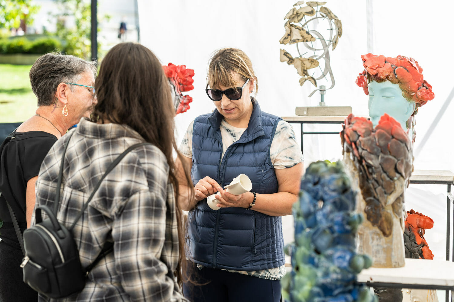 artist showing Art Fair visitors one of their handmade clay or ceramic pieces