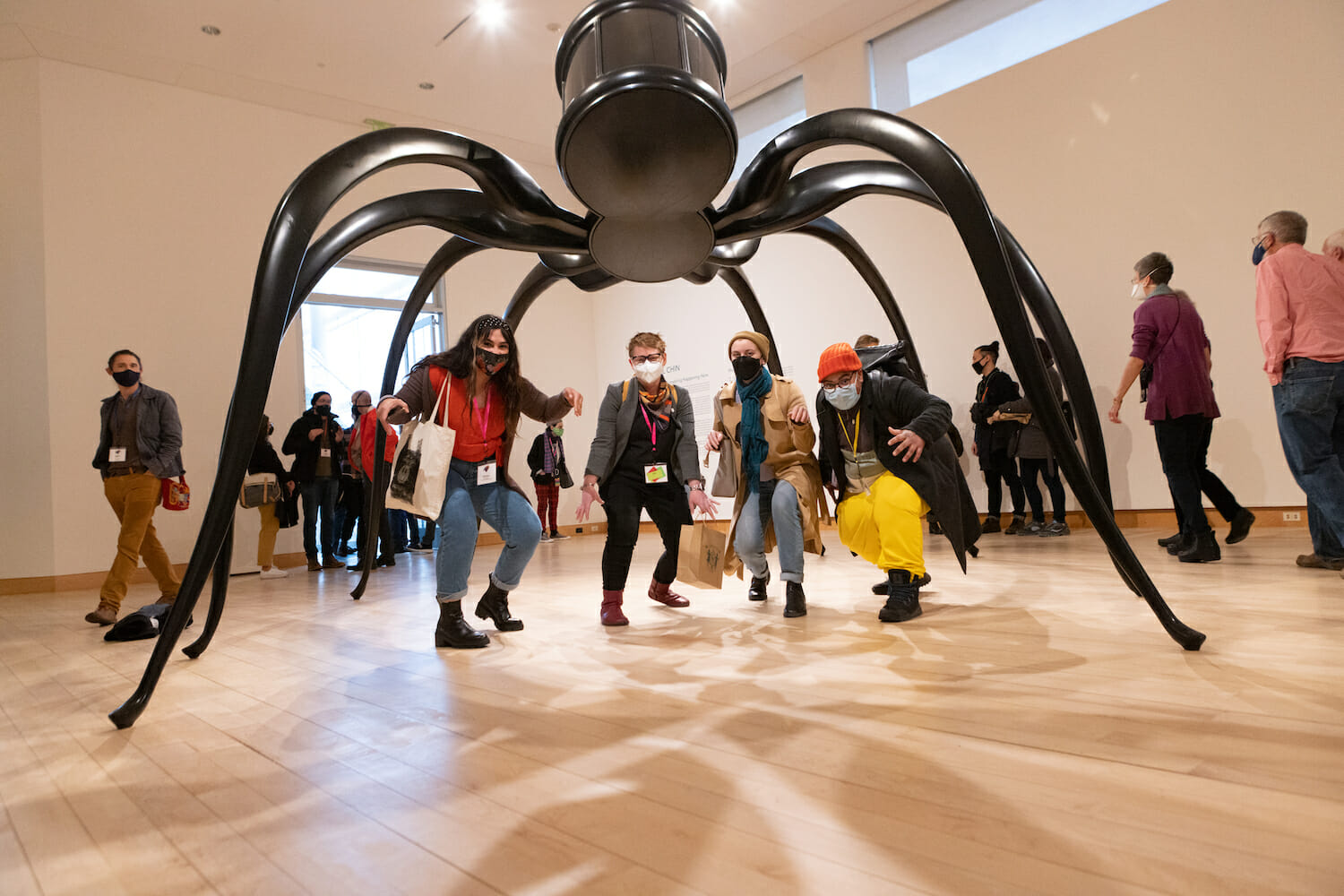 a group of people posing under a spider sculpture