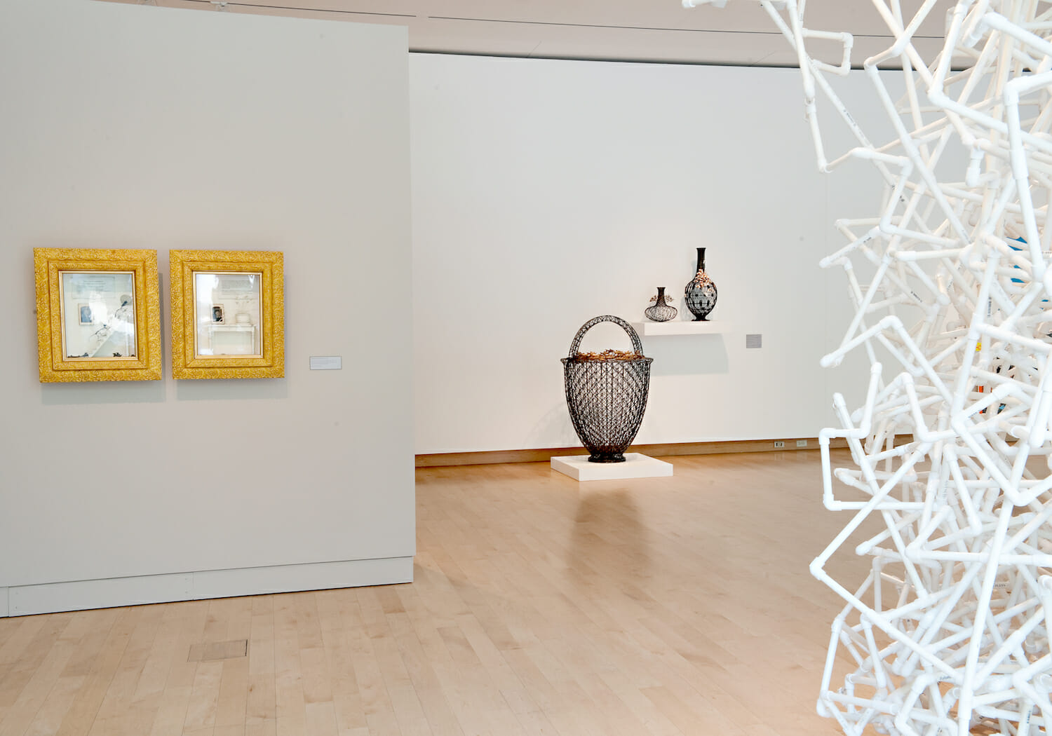 installation view of the 2010 Wisconsin Triennial featuring various sculptures and objects on shelves and flatforms and two mirrors hanging on a wall