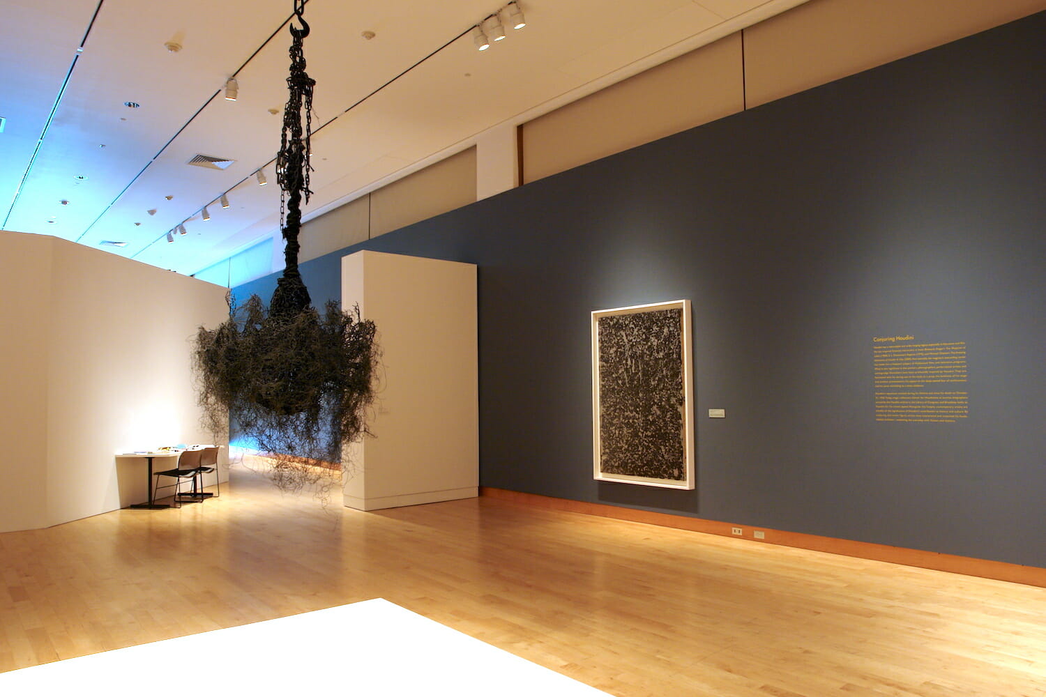 installation view of Houdini: Art and Magic featuring framed artwork and a hanging sculpture, similar to a chandelier