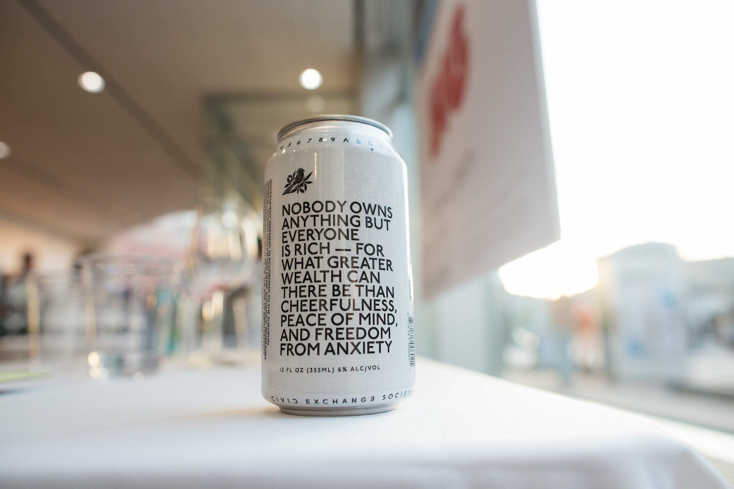 close up of a single beer can that says Nobody owns anything but everyone is rich – for what greater wealth can there be than cheerfulness, peace of mind, and freedom from anxiety