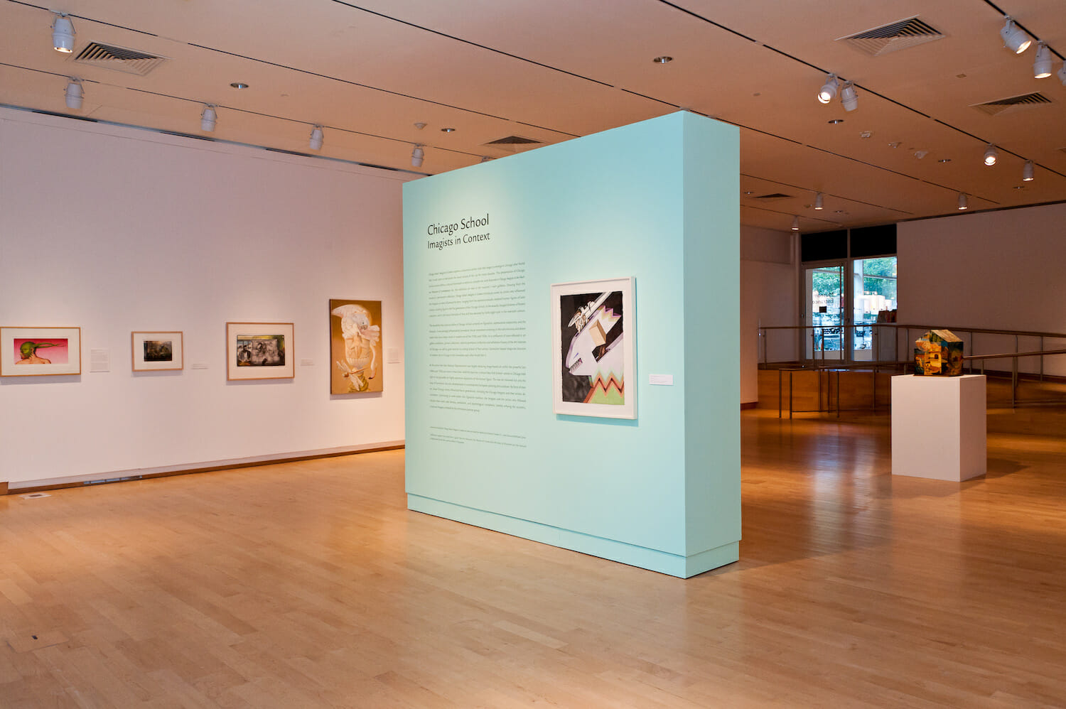 installation view of the exhibition Chicago School featuring title wall text and framed artworks hanging vertically across walls