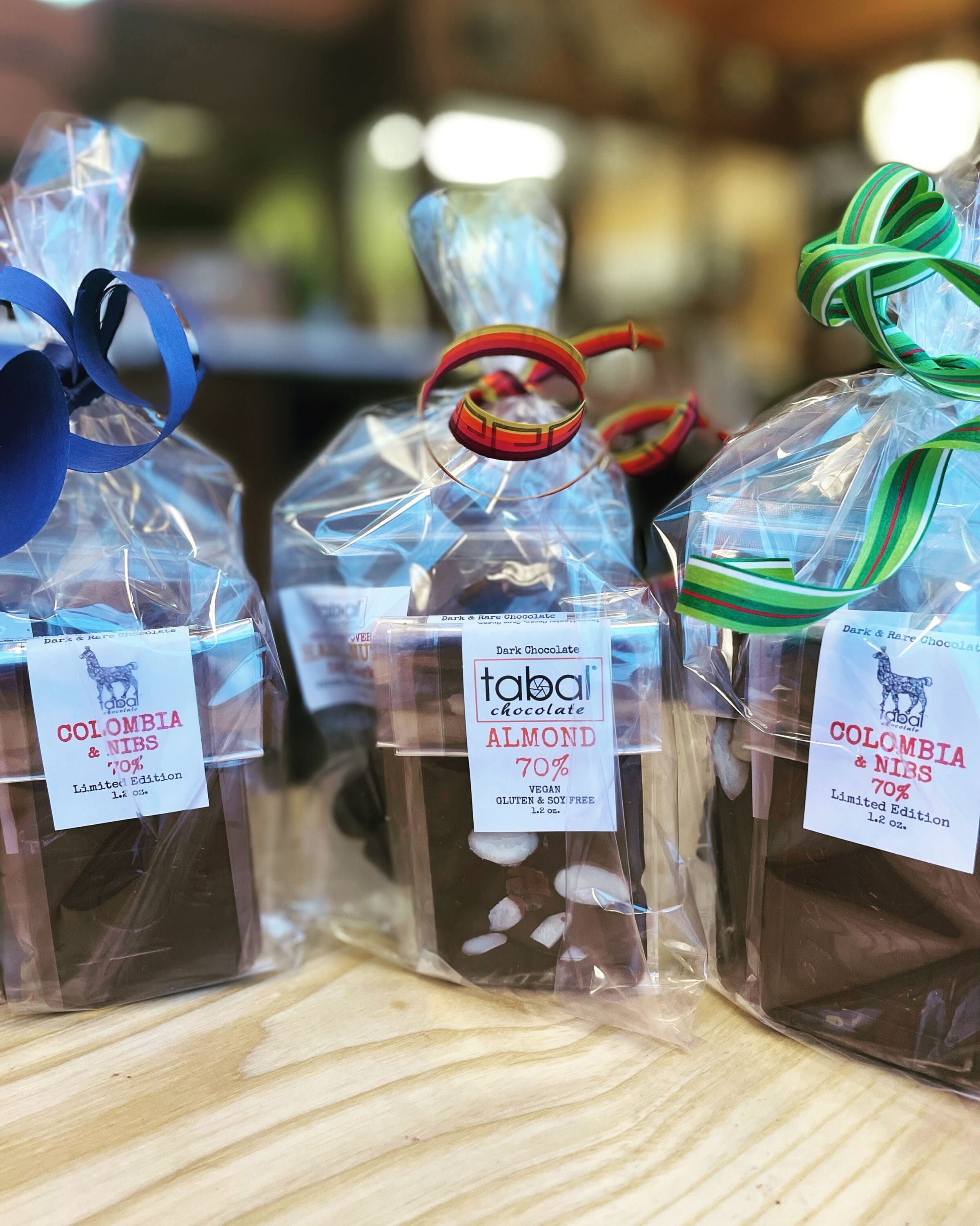 Various bags of chocolate with blue, red and green ribbons.