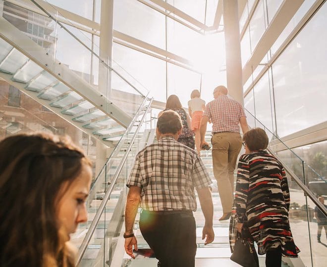 People walking up glass stairs.